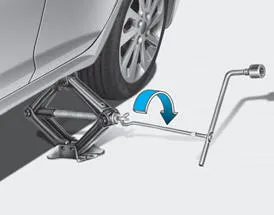 Hyundai Accent jack handle inserted and turning to raise the vehicle until the tire clears the ground